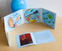 Photo du coffret 3 CDs de Jean René ouvert, montrant les trois CD illustrés et le livret intérieur posé sur une table en bois.